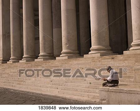 Stock Photo - Man Readning Newspaper, Stairs With Columns In Background; Naples, Italy. Fotosearch