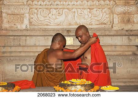 Stock Image - Man Receiving His New Robes As A Monk, Mahabodi Temple, Bodhgaya, Bihar, India. Fotosearch