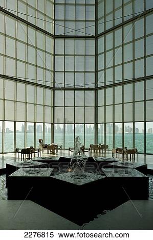 Stock Photography - Man relaxing in front of large window in the Museum of Islamic Art; Doha, Qatar. Fotosearch