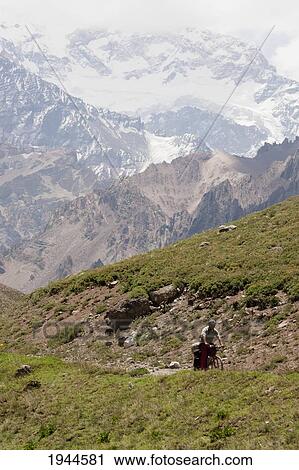 Stock Image - Man riding a mountain bike in Mount Aconcagua Provincial Park, Mendoza, Argentina. Fotosearch