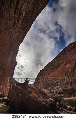 Stock Image - Man sits on a rock near the Redwall Canyon, Grand Canyon National Park; Arizona, United States of America. Fotosearch