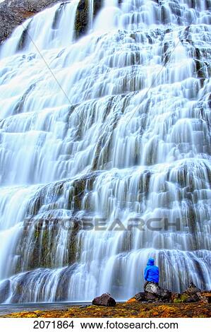 Picture - Man Sitting In Front Of The Waterfall Dynjandi, Central Westfjords, Iceland. Fotosearch