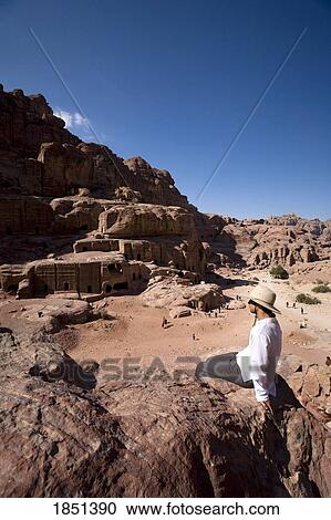 Stock Image - Man Sitting Near Monumental Nabataean Tombs. Fotosearch