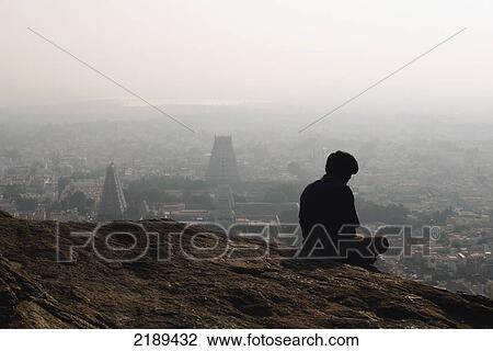 Man Sitting On A Boulder In Mediation With Arunachaleswarar Temple In Background, Tiruvannamalai, Tamil Nadu, India View Large Photo Image Stock Image - Man Sitting On A Boulder In Mediation With Arunachaleswarar Temple In Background, Tiruvannamalai, Tamil Nadu, India. Fotosearch