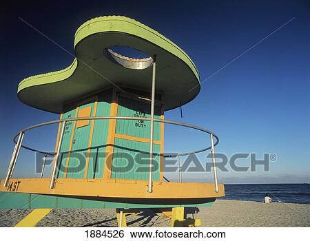Stock Photograph - Man Sitting On Beach In The Evening In Front Of Life Guard Tower. Fotosearch