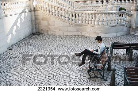 Picture - Man sitting on bench and reading; Tokyo, Japan. Fotosearch