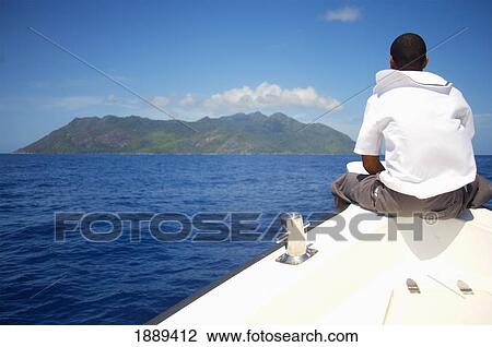 Man Sitting On Bow Of Boat Traveling Towards Island View Large Photo Image Stock Image - Man Sitting On Bow Of Boat Traveling Towards Island. Fotosearch