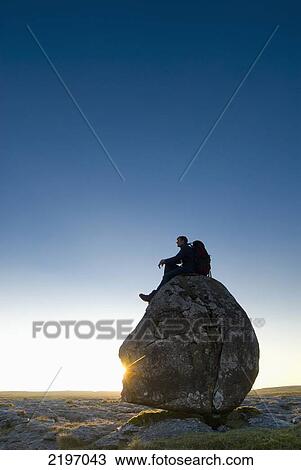 Man Sitting On Head-Shaped Boulder At Dusk, Twisleton Scars, Near Ingleton, Yorkshire Dales National Park, North Yorkshire, England. View Large Photo Image Stock Image - Man Sitting On Head-Shaped Boulder At Dusk, Twisleton Scars, Near Ingleton, Yorkshire Dales National Park, North Yorkshire, England.. Fotosearch