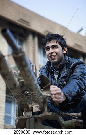 Stock Image - Man Sitting On Tank At The Amna Suraka (Red Security) Museum, Iraqi Kurdistan, Iraq. Fotosearch