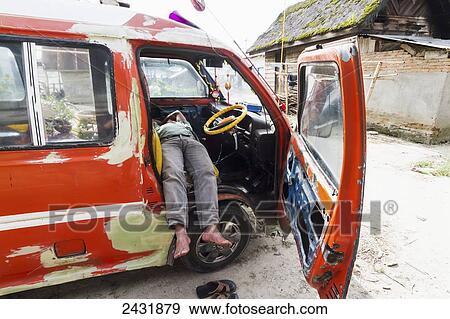 Stock Photo - Man sleeping in a van, Dokan, North Sumatra, Indonesia. Fotosearch