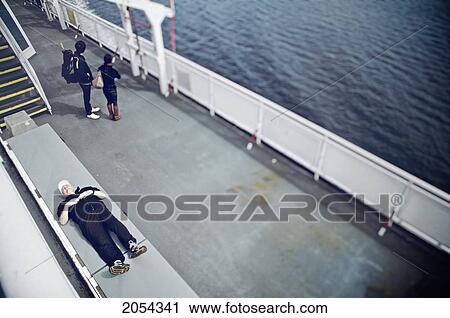 Stock Image - Man Sleeping On The Deck Of A Ferry, Swartz Bay, Bc. Fotosearch