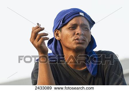 Man smoking a cigarette in Sunda Kelapa Harbour, Jakarta, Java, Indonesia View Large Photo Image Stock Photo - Man smoking a cigarette in Sunda Kelapa Harbour, Jakarta, Java, Indonesia. Fotosearch