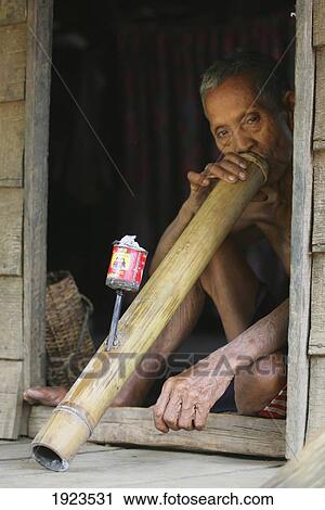 Stock Image - Man Smoking Large Water Pipe In Doorway, Bolaven Plateau, Champasak Province, Laos. Fotosearch