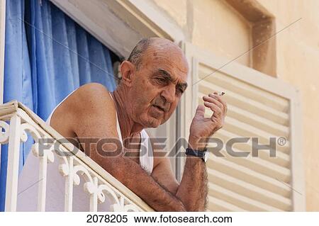Stock Photography - Man Smoking On A Balcony, Mdina, Malta. Fotosearch