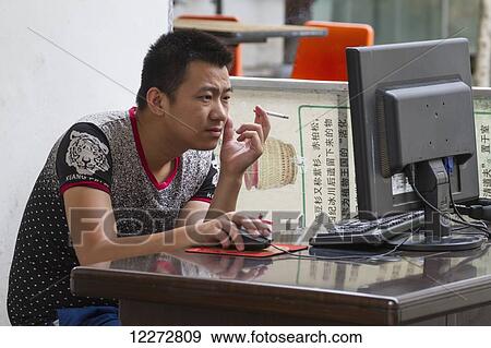 Stock Photo - Man smoking on a computer, Hongcun, Anhui, China. Fotosearch