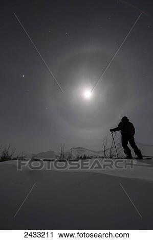 Man snowshoeing along the Dempster Highway under a moon glowing with rings; Yukon, Canada View Large Photo Image Stock Image - Man snowshoeing along the Dempster Highway under a moon glowing with rings; Yukon, Canada. Fotosearch