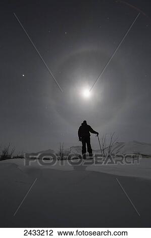 Man snowshoeing along the Dempster Highway under a moon glowing with rings; Yukon, Canada View Large Photo Image Stock Image - Man snowshoeing along the Dempster Highway under a moon glowing with rings; Yukon, Canada. Fotosearch