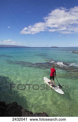 Stock Image - Man stand-up paddleboarding; Makena, Maui, Hawaii, United States of America. Fotosearch