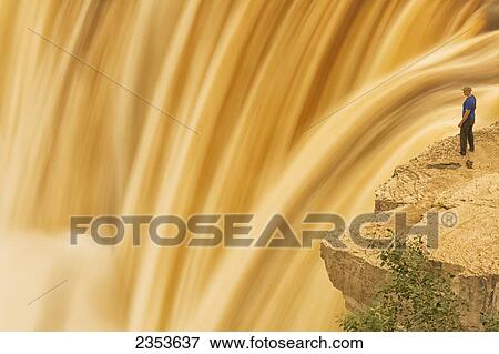Stock Photo - Man Standing At The Brink Of Alexandra Falls; Northwest Territories, Canada. Fotosearch