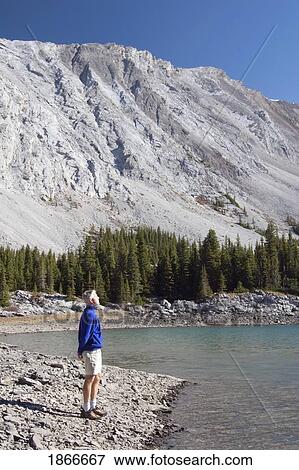 Man Standing By A Mountain Lake View Large Photo Image Stock Photo - Man Standing By A Mountain Lake. Fotosearch
