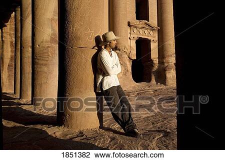 Stock Image - Man Standing By Royal Tomb In Petra. Fotosearch