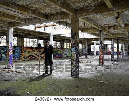 Stock Photo - Man standing in abandoned industrial building covered in graffiti; Montreal, Quebec, Canada. Fotosearch