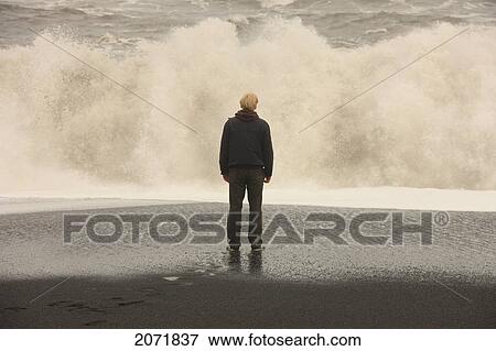 Man Standing In Front Of Large Waves On A Black Sand Beach, Near Vik, Iceland View Large Photo Image Stock Photo - Man Standing In Front Of Large Waves On A Black Sand Beach, Near Vik, Iceland. Fotosearch
