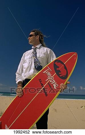 Man Standing On Beach In Business Suit Holding A Surfboard. View Large Photo Image Stock Image - Man Standing On Beach In Business Suit Holding A Surfboard.. Fotosearch