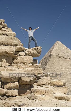 Stock Image - Man Standing On Part Of A Pyramid In The Desert. Fotosearch