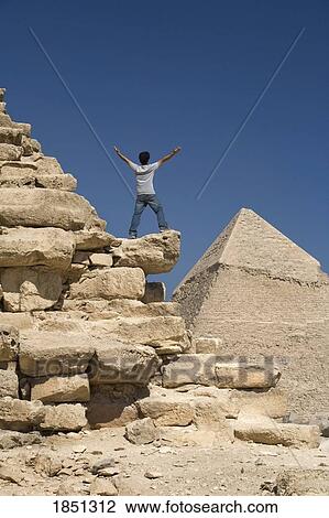 Stock Image - Man Standing On Part Of A Pyramid In The Desert. Fotosearch