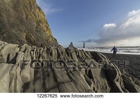 Man standing on the south shore of Iceland near Vik watching the waves hit the shoreline; Iceland View Large Photo Image Stock Photography - Man standing on the south shore of Iceland near Vik watching the waves hit the shoreline; Iceland. Fotosearch