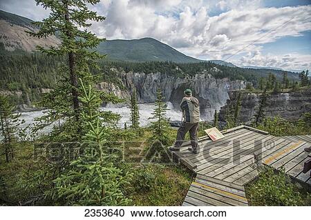 Man Stands At The Lookout Above Virginia Falls In Nahanni National Park Reserve; Northwest Territories, Canada View Large Photo Image Stock Image - Man Stands At The Lookout Above Virginia Falls In Nahanni National Park Reserve; Northwest Territories, Canada. Fotosearch