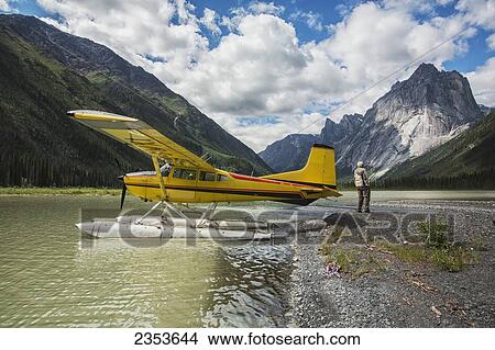 Man Stands On The Shores Of Glacier Lake By Float Plane; Northwest Territories, Canada View Large Photo Image Picture - Man Stands On The Shores Of Glacier Lake By Float Plane; Northwest Territories, Canada. Fotosearch