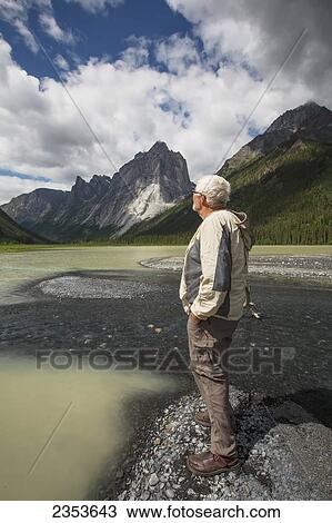 Stock Image - Man Stands On The Shores Of Glacier Lake; Northwest Territories, Canada. Fotosearch