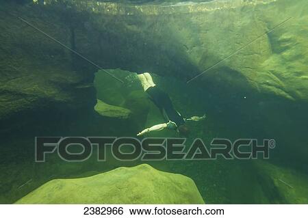 Stock Photograph - Man swimming through underwater arch in one of the Fairy Pools in Coire na Creiche, Black Cuillin; Isle of Skye, Scotland. Fotosearch