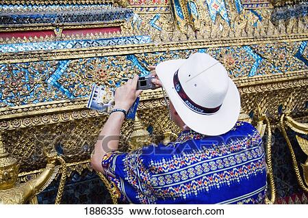 Stock Photography - Man Taking Pictures Of Bot Walls Of Wat Phra Kaeo At Grand Palace. Fotosearch