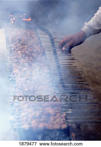 Stock Photo - Man Tending Lamb Kebabs At The Hotan Sunday Market. Fotosearch