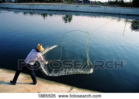 Stock Photography - Man Throwing A Fishing Net Into A Canal. Fotosearch