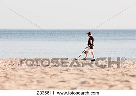 Stock Image - Man Using Metal Detector On Beach; Bournemouth, Dorset, England, Uk. Fotosearch
