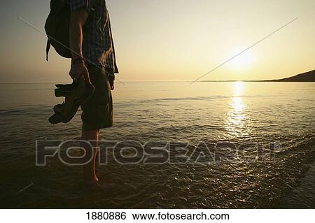Man Wading In Water On Beach At Sunset View Large Photo Image Stock Photograph - Man Wading In Water On Beach At Sunset. Fotosearch