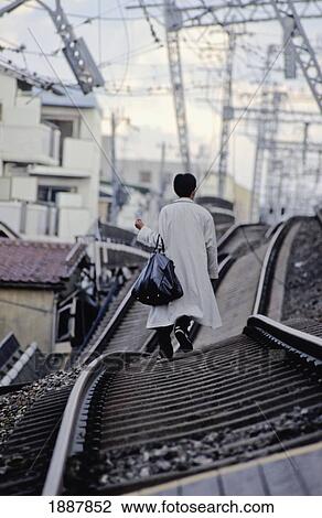 Stock Image - Man Walking On Railway Lines After Earthquake. Fotosearch