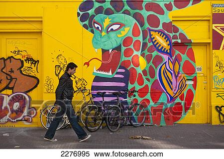 Stock Photography - Man Walking Past Large Mural Of Snake And Businessman Painted On Front Of Building, Amsterdam, Holland.. Fotosearch