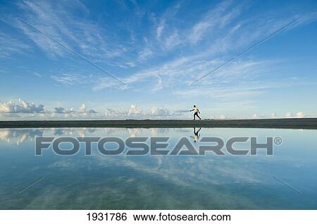 Stock Photograph - Man Walking Past Shallow Pond, Brighton Beach, Barbados.. Fotosearch