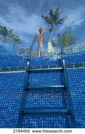 Stock Photography - Man walking past steps to swimming pool, Ocean Blue Hotel, Punta Cana, Dominican Republic.. Fotosearch