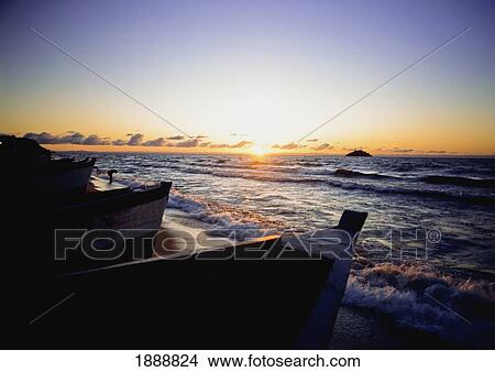 Picture - Man Washing In The Surf At Dawn Beside Fishing Boats. Fotosearch