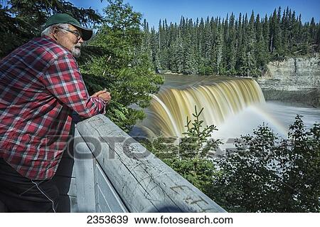 Man Watching The Kakisa River Flow Over Lady Evelyn Falls Near Kakisa; Northwest Territories, Canada View Large Photo Image Stock Photo - Man Watching The Kakisa River Flow Over Lady Evelyn Falls Near Kakisa; Northwest Territories, Canada. Fotosearch