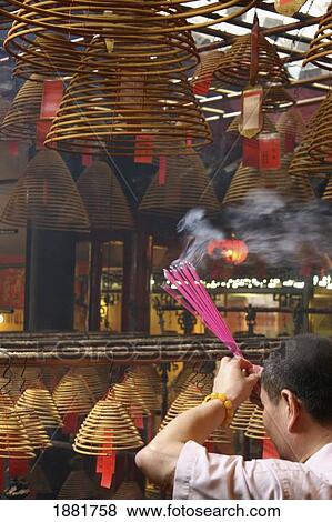 Man With Smoking Incense Spirals At The Man Mo Temple View Large Photo Image Stock Photo - Man With Smoking Incense Spirals At The Man Mo Temple. Fotosearch