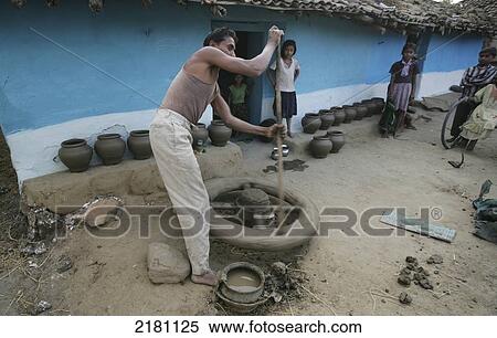Stock Photography - Man working on a pottery wheel with his family members watching, Potters village; Madhya Pradesh, India. Fotosearch