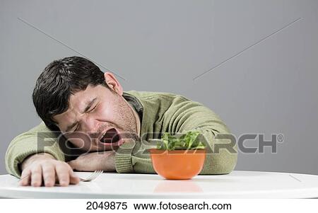 Stock Photography - Man Yawning At A Table With Salad. Fotosearch