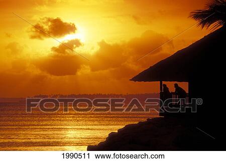 Stock Image - Marshall Islands, Majuro Atoll, Couple Watch Sunset From Porch. Fotosearch